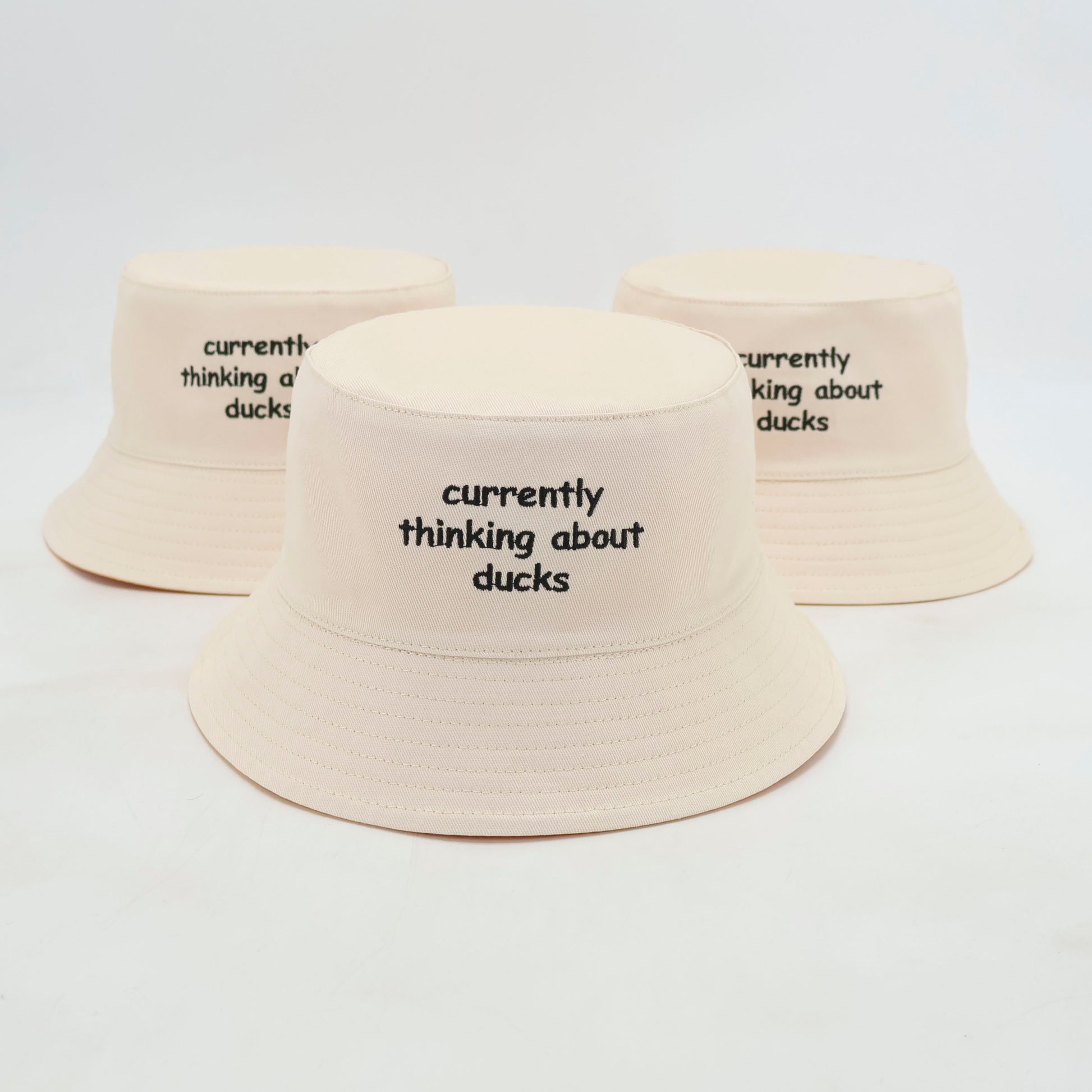 White duck bucket hat with thinking about ducks text.