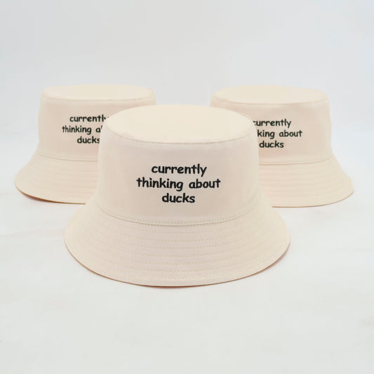 White duck bucket hat with thinking about ducks text.