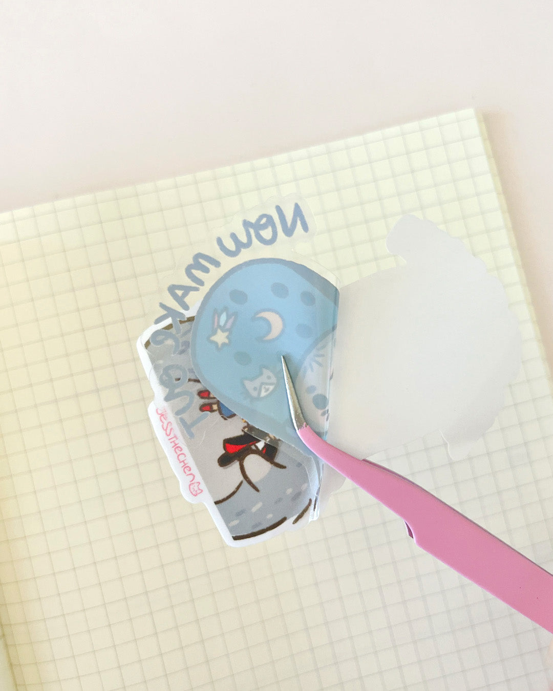 Die-cut sticker Now Make Out being applied with tweezers.