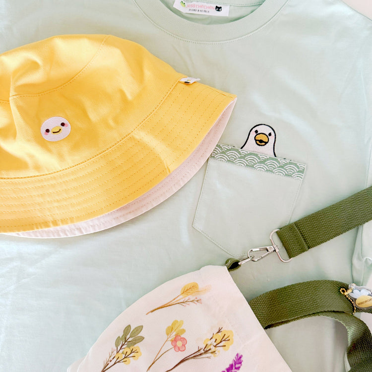 Duck embroidered pocket tee with reversible bucket hat and floral mini tote bag outfit flatlay